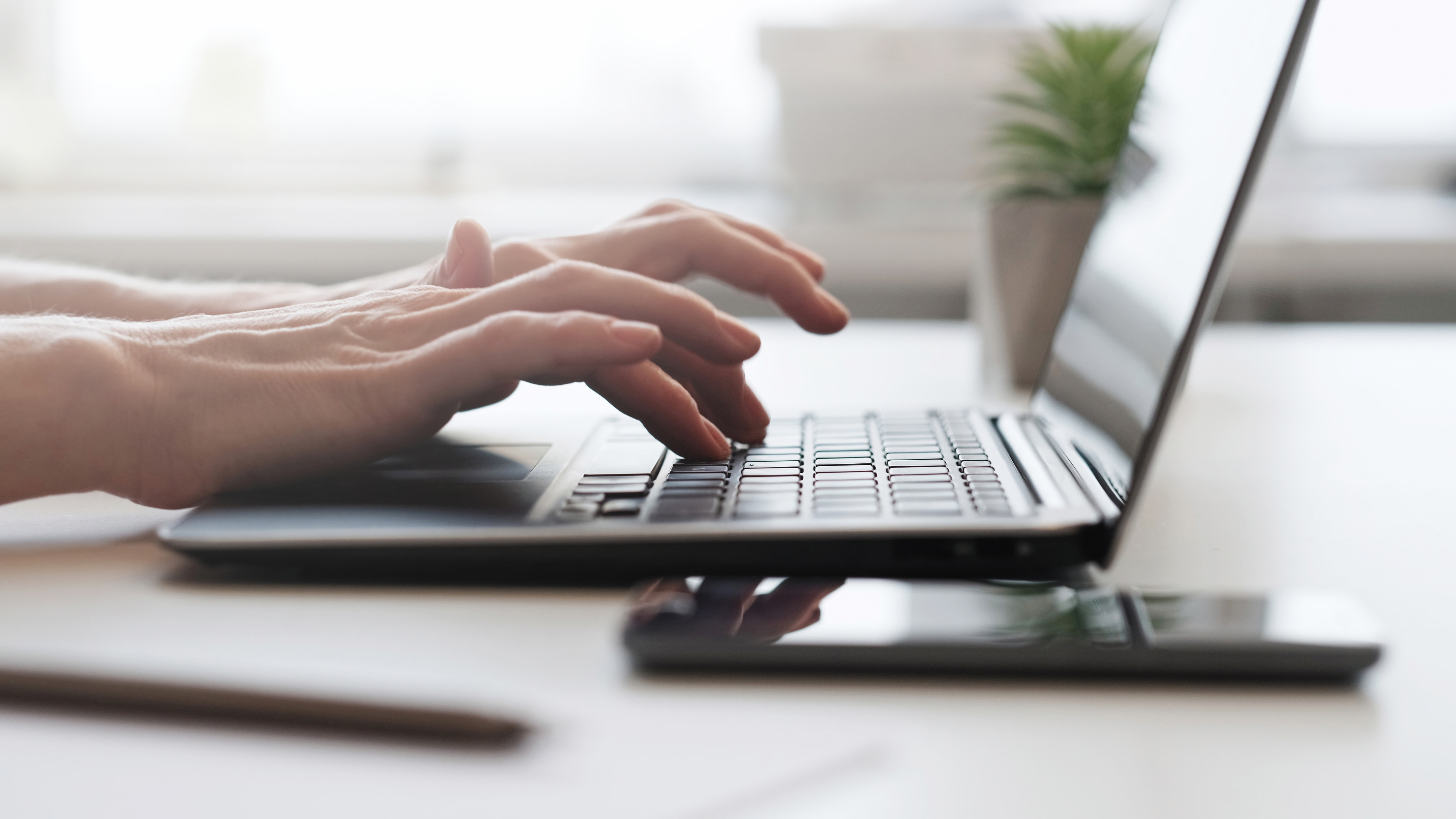 Hands typing on a laptop keyboard.