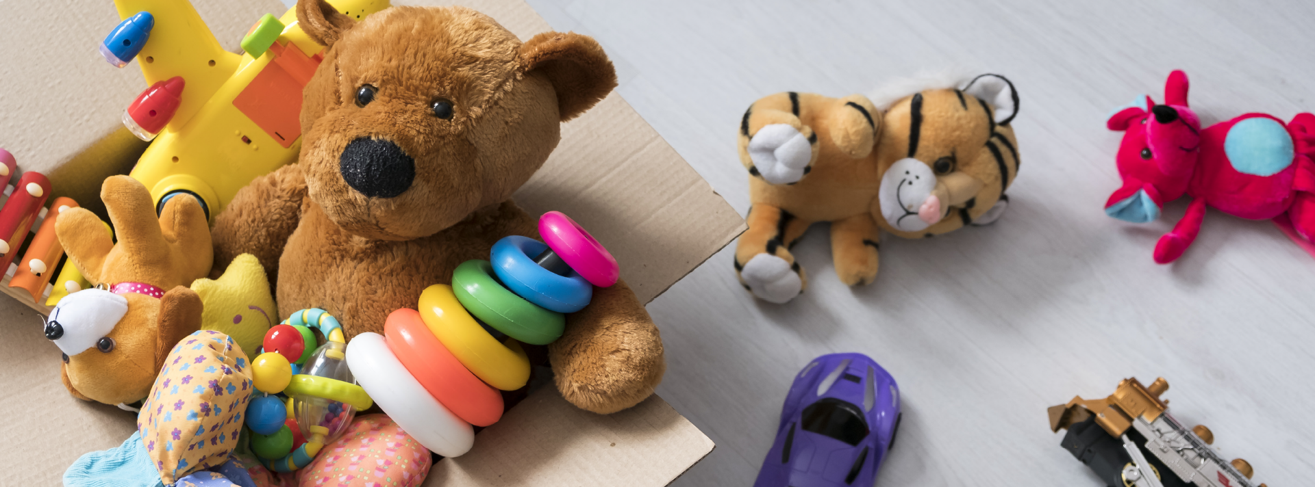 Children's toys, including a stuffed bear, a stuffed tiger, stacking rings, and a toy car